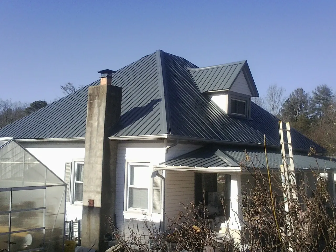Dark blue standing seam metal roof on a white farmhouse with dormer — Slate & Tile Roof Repair by Roofing Brothers in Mascot