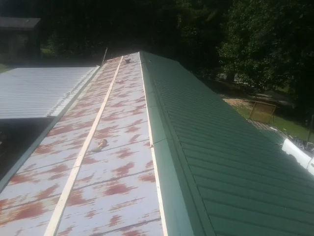 Old rusted panels beside newly installed green metal roofing — Wind Damage Roof Repair by Roofing Brothers in Mascot