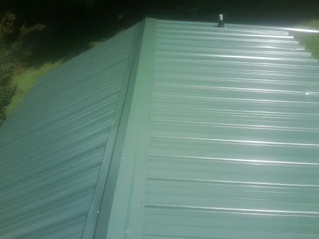 New green metal panels meeting at the ridge of a roof — Flat Roof Repair work by our crew in Mascot