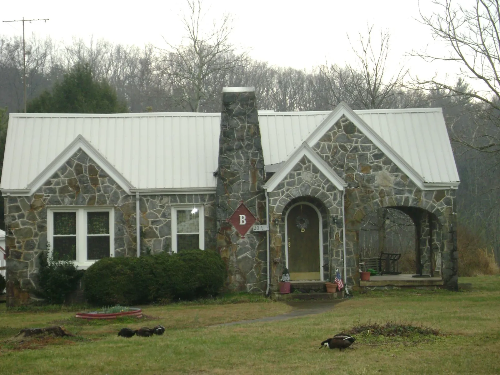 White metal roof on a stone cottage with steep gables in Mascot