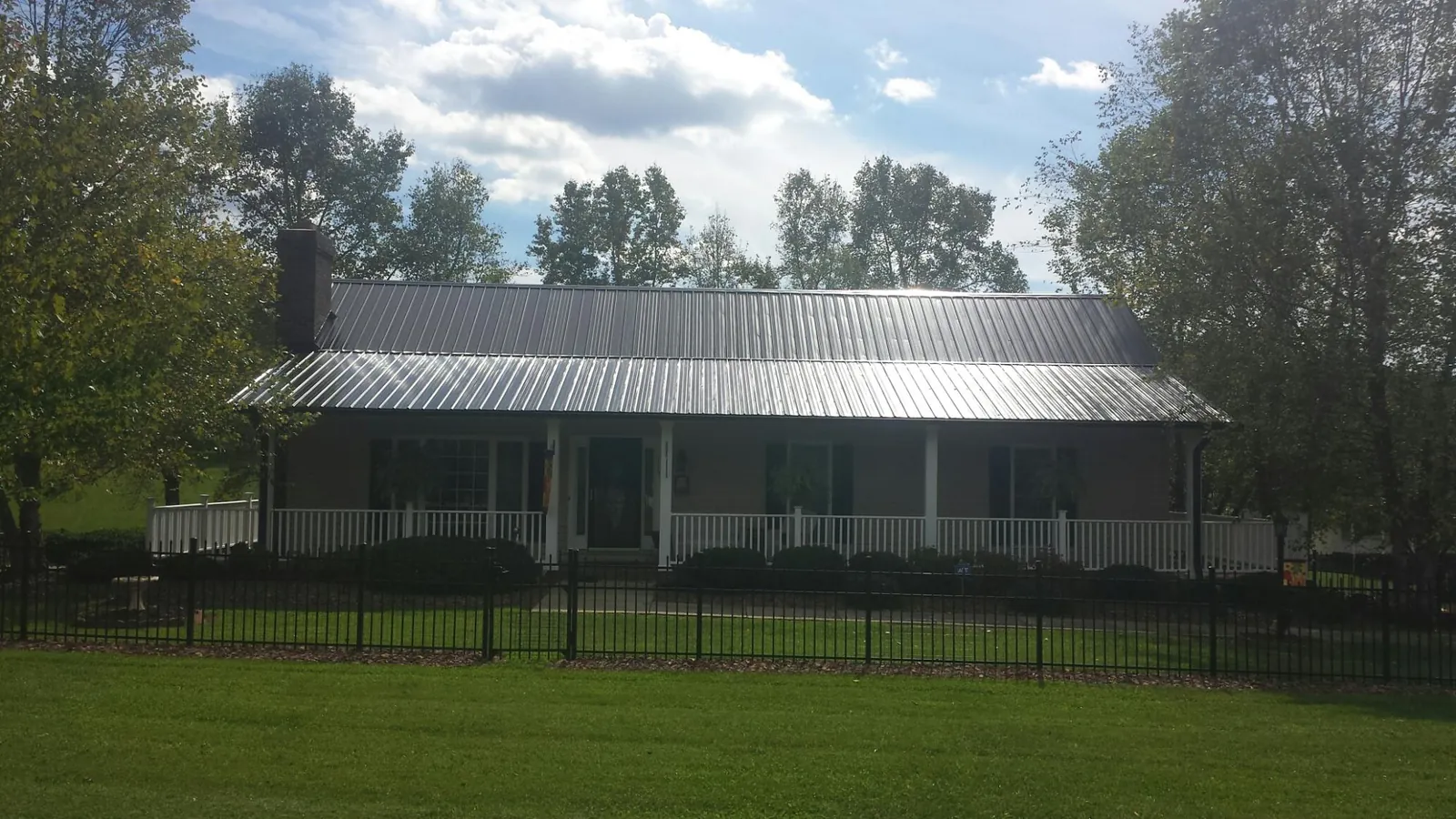 Gray metal roof on a brick ranch with a full width front porch — Gutter Guard Installation work by our crew in Mascot